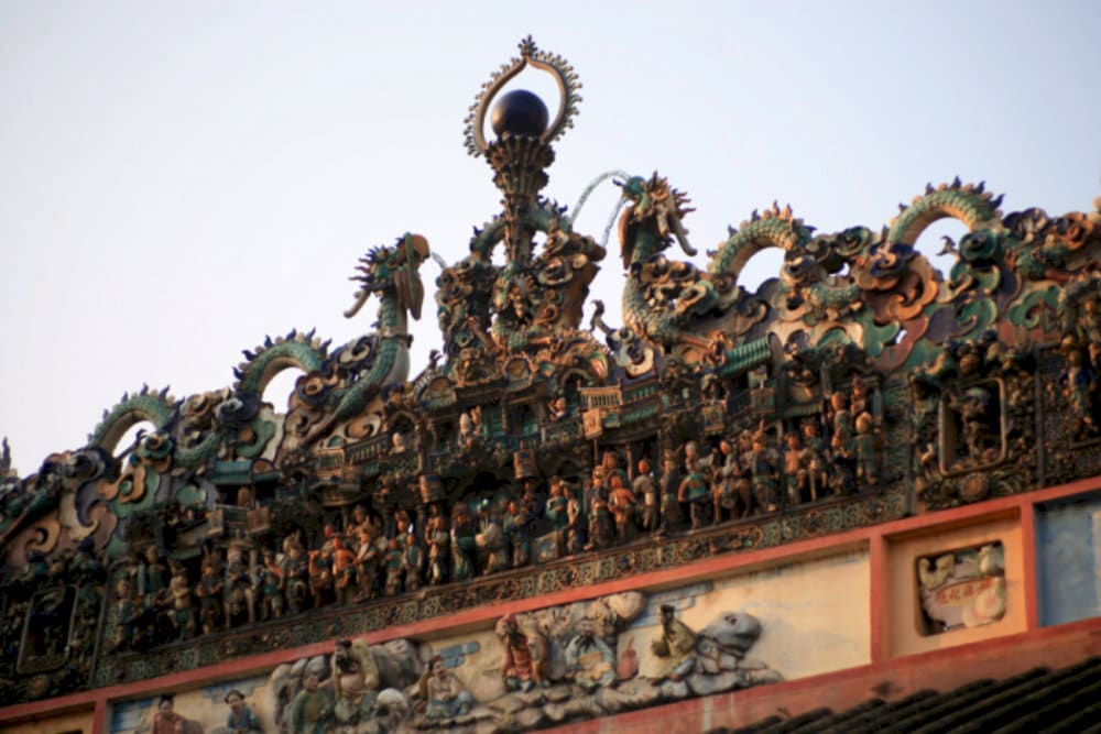 On the temple roof, prominent ceramic reliefs depict dragons, often the image of "two dragons fighting for a pearl" symbolizing nobility and power